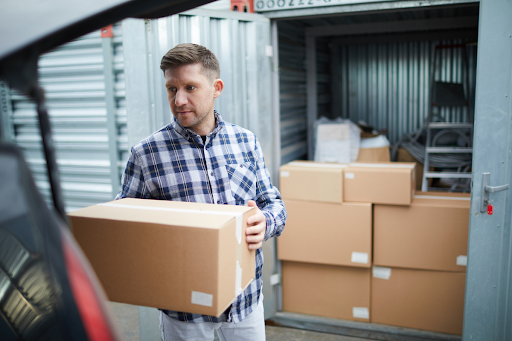 man holding box outside of shipping container